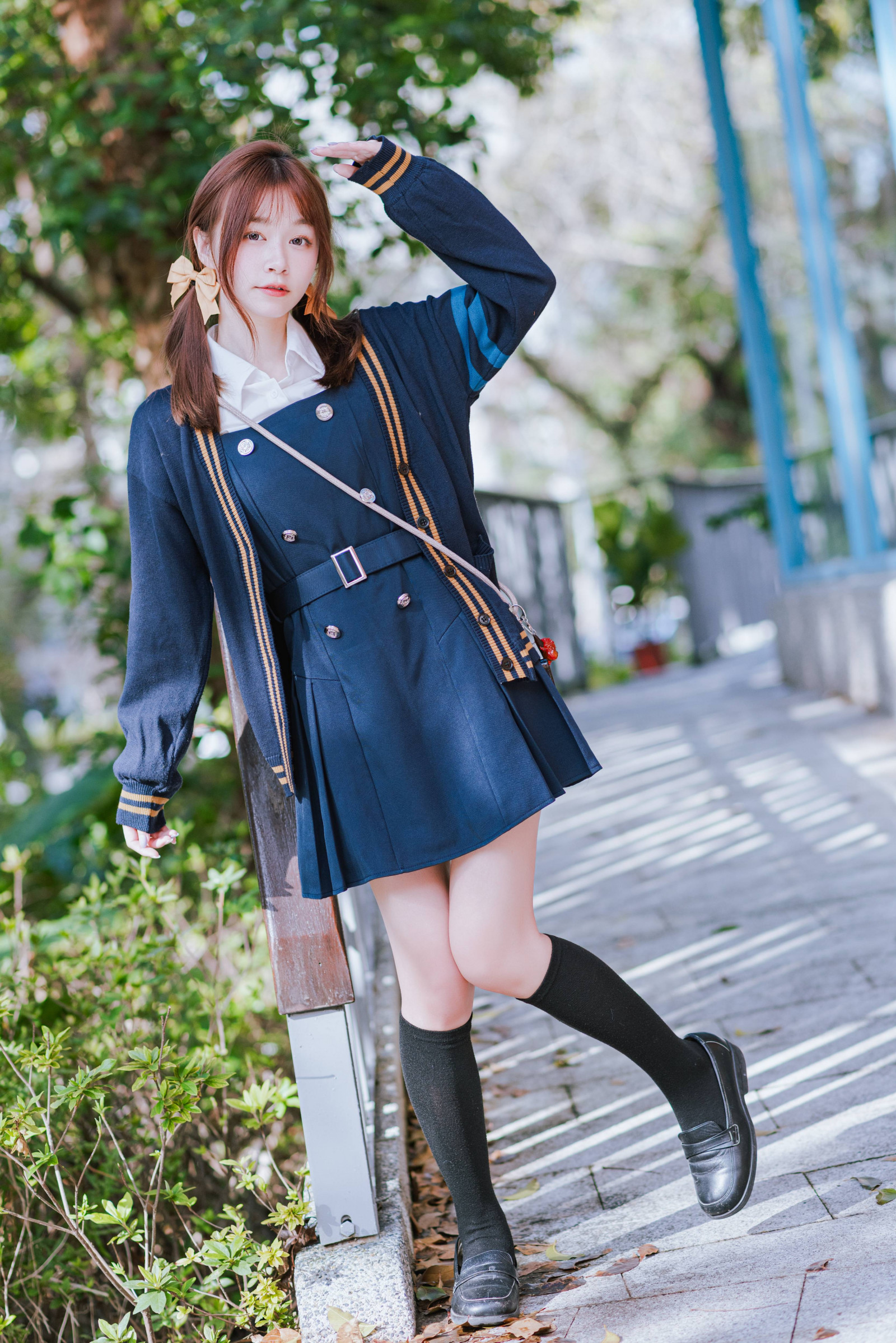 bangs, cardigan, leaning, outdoor, pleated skirt, portrait, railing, school uniform, soft focus, sunlight, woman, yellow bow