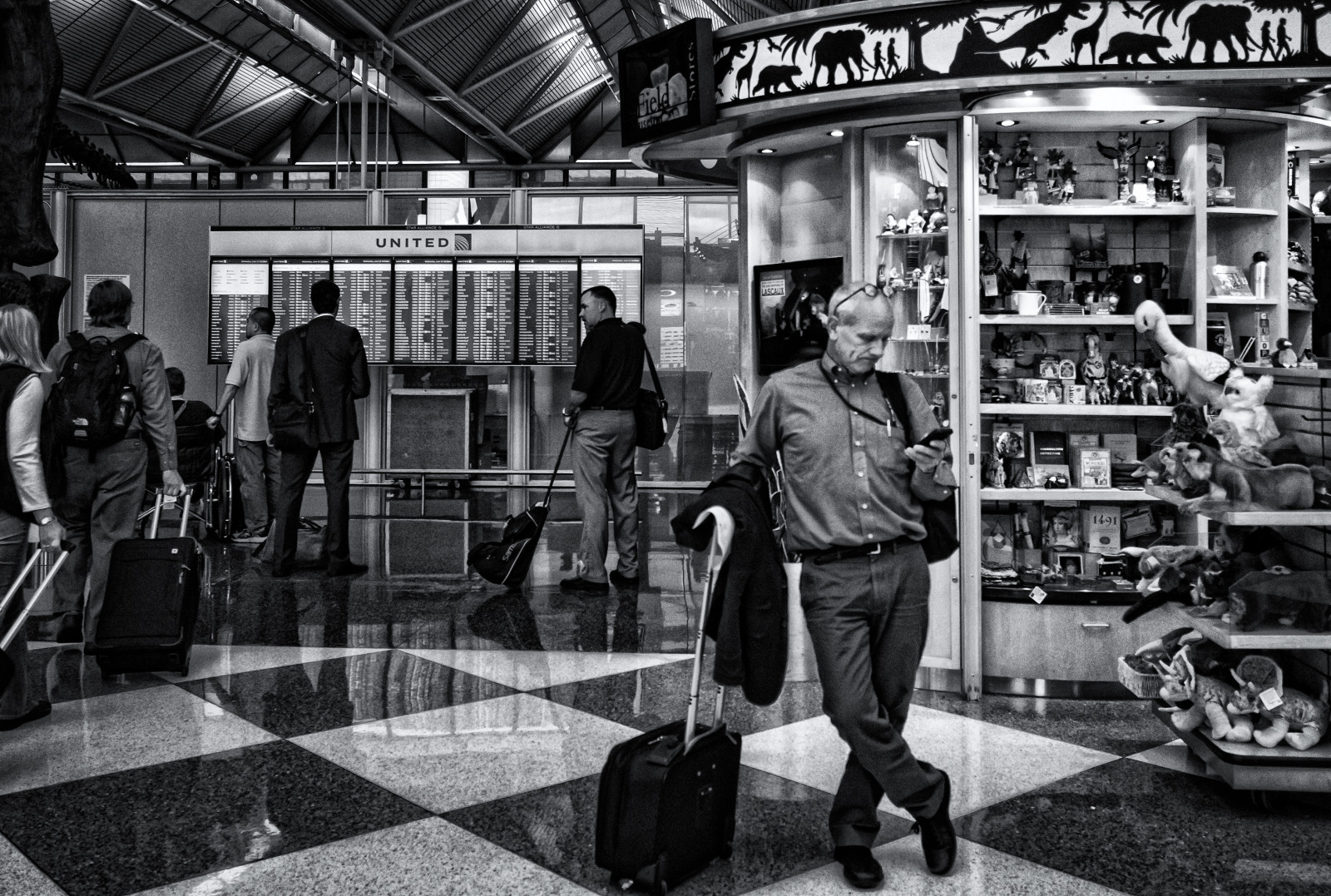 persone, nero, giocattoli, monocromo, finestra, città, strada, strada, fotografia, camicia, pantaloni, in piedi, aeroporto, scaffali, scacchi, cellulare, Chicago, valigia, piastrella, infrastruttura, Mono, bianco e nero, viaggio, pavimento, linea, stile, streetphotography, completo da uomo, ricohgr, istantanea, zaino, comunicazione, area urbana, bianco e nero, fotografia in bianco e nero, anneworner, OHare, spazio pubblico, vending, spensierato, United Airlines, Imbottiti, Chicagoohare, Incantevole, nessun problema, bagaglio a mano, Volo